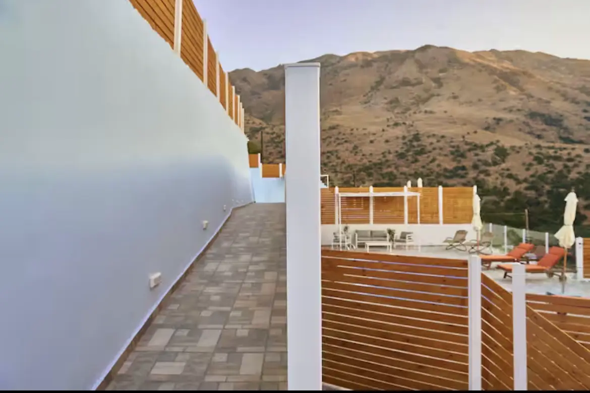 Paved outdoor walkway and wooden fencing leading to the private terrace area of Suite 1 with hills in the background.