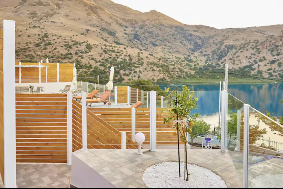 Stone patio with wooden privacy fencing overlooking a beautiful lake and mountain landscape